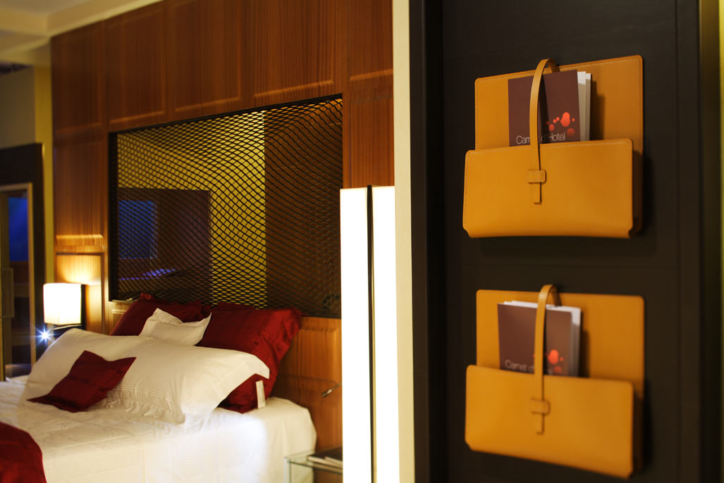 Letto della camera con la rete di ottone e le tasche in pelle a parete.