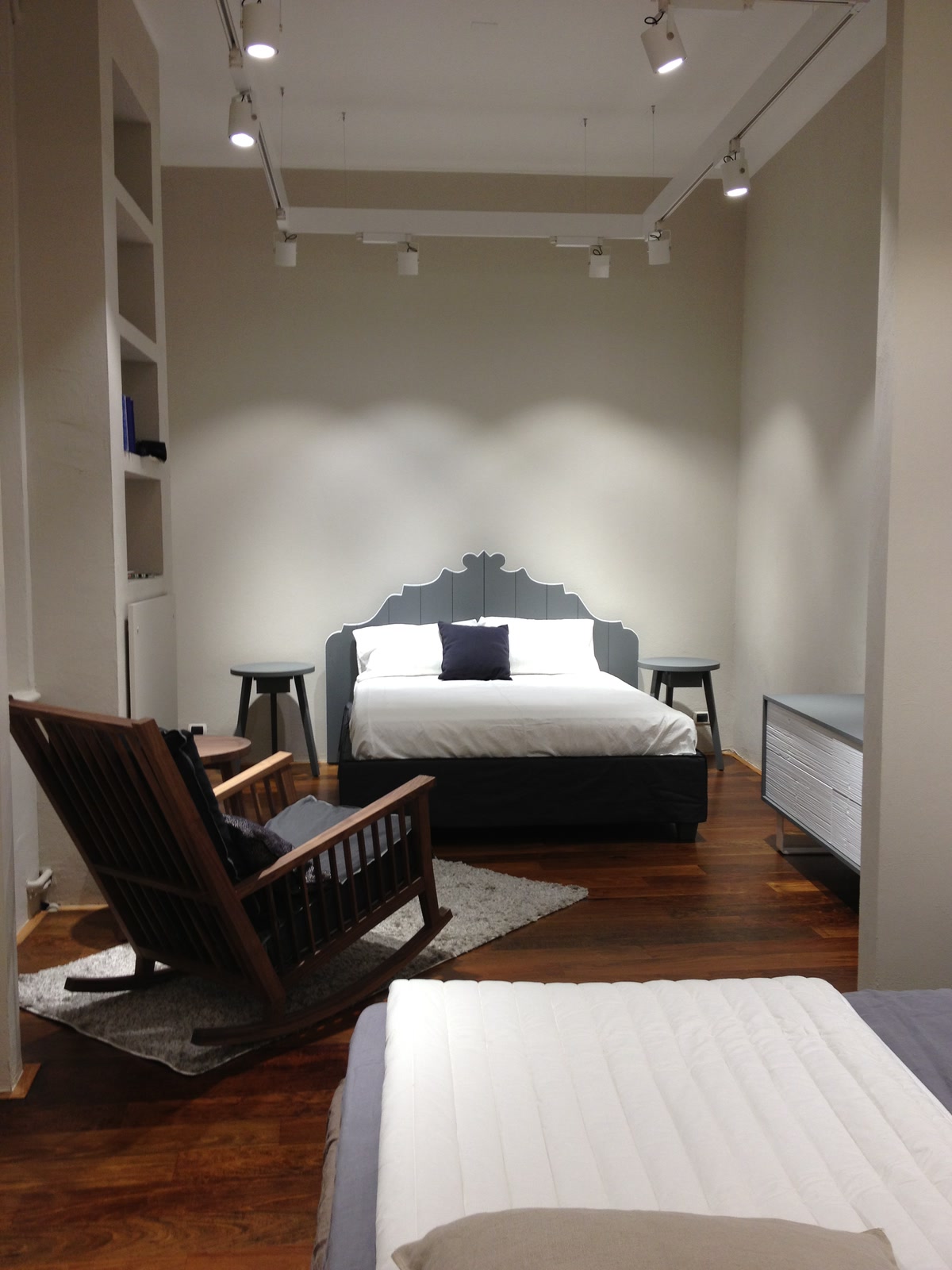 Ambiente dello showroom con letto esposto e poltrona in legno.