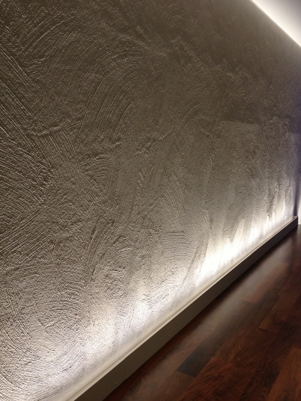 Dettaglio della parete materica dello showroom sotto luce radente.