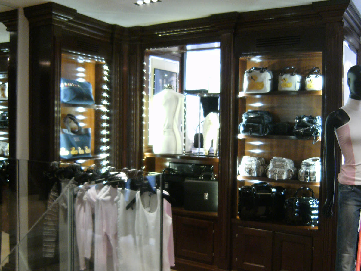 Le vetrine illuminate con le borse, dentro la boiserie in legno scuro.