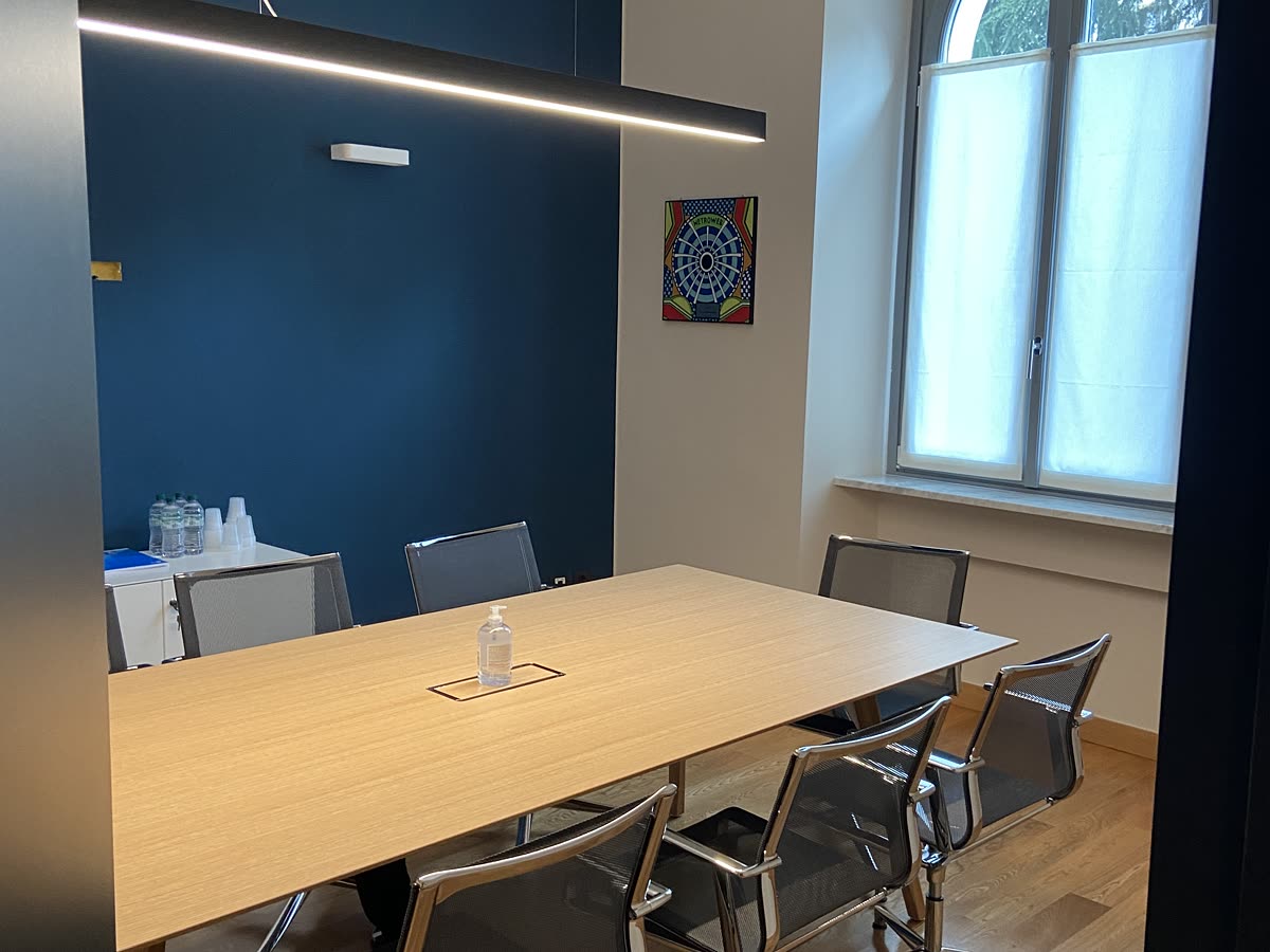 Sala riunioni con la parete blu e il tavolo in legno chiaro.