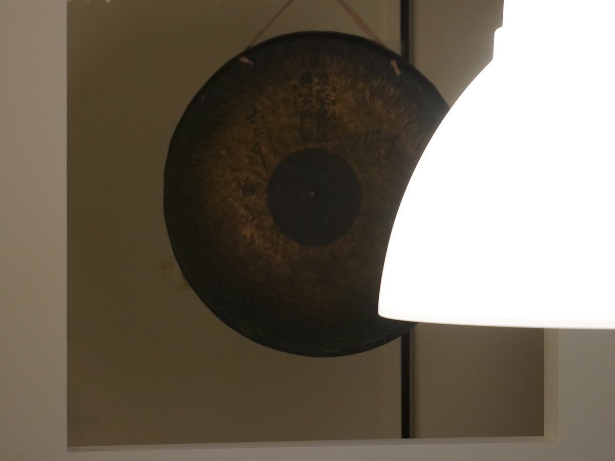 Dettaglio della parete con la lampada e l’opera appesa.