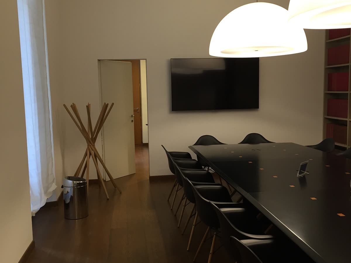 Sala riunioni con tavolo scuro e libreria sul fondo.