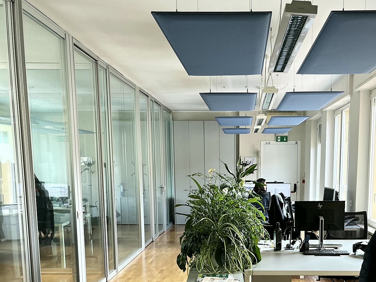 Il corridoio degli uffici, con le pareti vetrate e i pannelli acustici a soffitto.