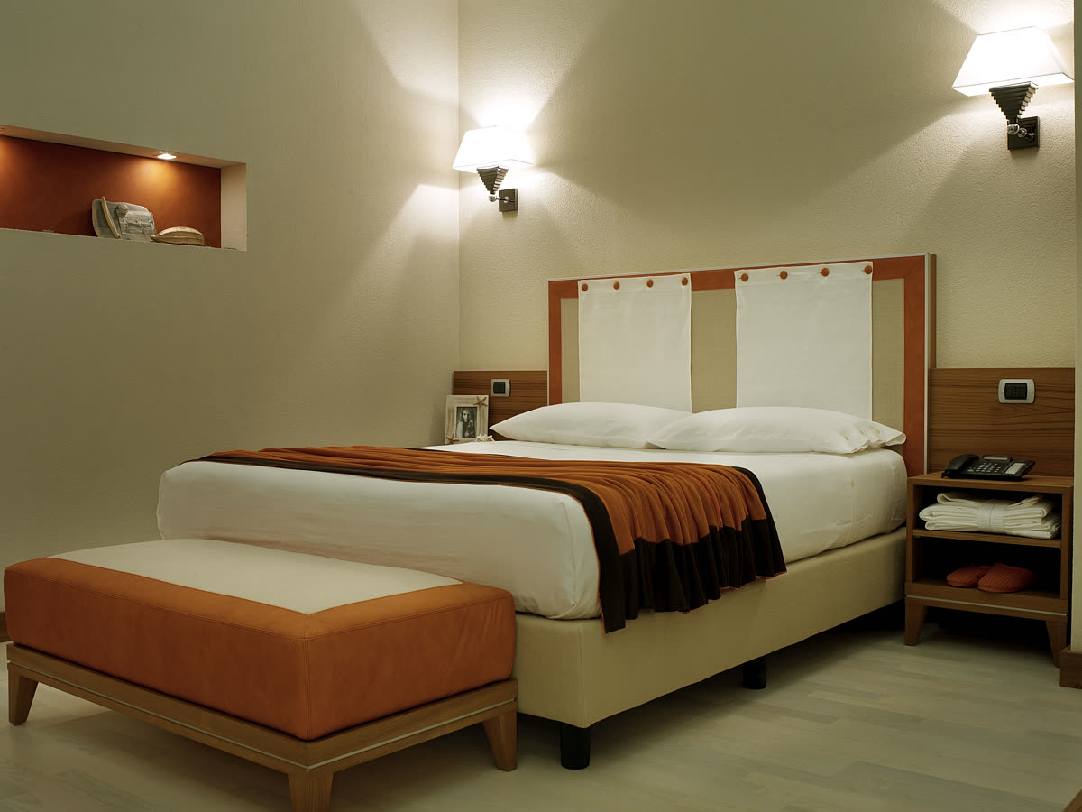 La camera prototipo: letto, pouf e testata in legno.
